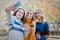 Cheerful attractive three young women best friends having fun together outside and making selfie.