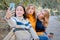 Cheerful attractive three young women best friends having fun together outside and making selfie.