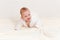 A cheerful baby girl in a Terry robe and a diaper crawls on the bed after bathing