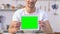 Cheerful bachelor holding tablet with green screen, food delivery service app