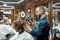 Cheerful barber drying long hair of young hipster guy sitting in in armchair in the modern barbershop