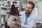 Cheerful bearded male veterinarian examining beautiful dog