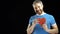 Cheerful bearded man in blue tshirt holds one red heart shape. Love, single, romance, dating, relationship concepts