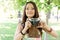 Cheerful beautiful girl talks pictures with vintage camera in summer park. Young woman photographer posing outdoor with camera