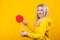 Cheerful beautiful young blonde woman in casual yellow sporty clothes play ping pong, holding a ball and racquet