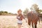 Cheerful beautiful young woman cowgirl with her horse on ranch