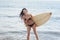 Cheerful bikini woman holding surfboard at beach