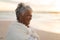 Cheerful biracial senior bride with short white hair standing at beach during sunset