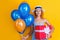 cheerful birthday woman with present and balloons. birthday woman with present isolated on yellow. birthday woman with