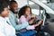 Cheerful black family checking car salon before buying new automobile, sitting inside auto, going on test drive