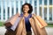 Cheerful Black Female Holding Paper Shopping Bags Posing Outdoors