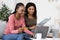 Cheerful black girlfriends booking tickets online, using laptop