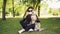 Cheerful blogger pet owner is taking selfie with her dog using smartphone, human and animal are sitting on lawn in the