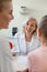 Cheerful blonde doctor in white robe sitting in front of her patients