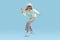 Cheerful blonde woman in furry bucket hat, sunglasses, mint cotton funny dancing on blue background.