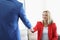 Cheerful blonde young lady greeting man with handshake sitting on sofa