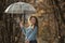 Cheerful blue-eyed girl with wavy hair dance with transparent umbrella in hands in autumn forest or park