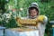 Cheerful boy beekeeper in protective suit near beehive. Honeycomb with honey. Organic food concept. The most useful organic honey