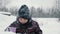 Cheerful boy drinking hot tea from cup in snowy forest at winter walk. Boy enjoying winter tea while walking at cold day