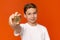 Cheerful boy holding golden bitcoin, orange studio background