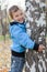 Cheerful boy hugging birches, autumn park