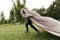 Cheerful boy running with a flying blanket in the park