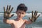 Cheerful boy teenager shows his hands in the healing healing mud from the sea