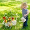 Cheerful boy with watering can and flowers