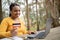 Cheerful brazilian lady holding credit card, typing on laptop, enjoying online sales, sitting in city park, free space