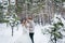 Cheerful bride and groom in beige knitted pullovers in snowy forest. Newlyweds looks at each other. Winter