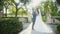 Cheerful bride and groom are kissing in the middle of alley in the green park