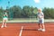 Cheerful brother feeling happy playing tennis with sister