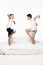 Cheerful brothers imitating birds while standing on bed on white background