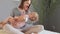 Cheerful brown haired woman baby at home singing rockabye song embracing kid holding infant daughter in hands and smiling sleep