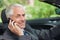 Cheerful businessman on the phone driving expensive cabriolet