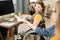 Cheerful businesswoman in wheelchair taking clipboard with financial document