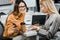 Cheerful businesswomen using smartphone together at workplace