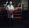 Cheerful butcher holding sausages in the storage room.