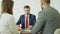 Cheerful car dealership employee is shaking hands with young buyer handsome man after signing documents then giving key