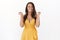 Cheerful carefree attractive brunette woman in yellow dress, grinning joyfully, squinting and smiling toothy