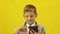 Cheerful caucasian boy 7 years old in a jacket holds a bank card and a smartphone in his hands. Online shopping theme children. St