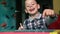 Cheerful Caucasian boy preschooler learning to write on the blackboard with chalk at home. Writes words and laughs with pleasure.