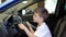 A cheerful Caucasian boy is sitting in the salon of a new car in a car dealership and looks at the interior of the salon