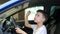 A cheerful Caucasian boy is sitting in the salon of a new car in a car dealership and looks at the interior of the salon