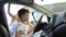 A cheerful Caucasian boy is sitting in the salon of a new car in a car dealership and looks at the interior of the salon