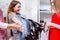 Cheerful Caucasian girl buying or choosing jeans with a shop assistant in a clothing store