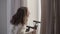 Cheerful caucasian girl holding video stabiliser and laughing. Young brunette woman standing in white bathrobe in the