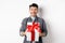 Cheerful caucasian guy holding surprise gift, receive present on holiday and smiling thankful, looking grateful at