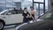 Cheerful caucasian man and woman dancing ballet in car dealership, slowmo. Male and female ballet dancers moving in auto