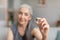 Cheerful caucasian older gray-haired lady hold pill in hand for treatment of disease in living room interior